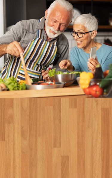 Man and woman cooking while following instructions on a smart phone.