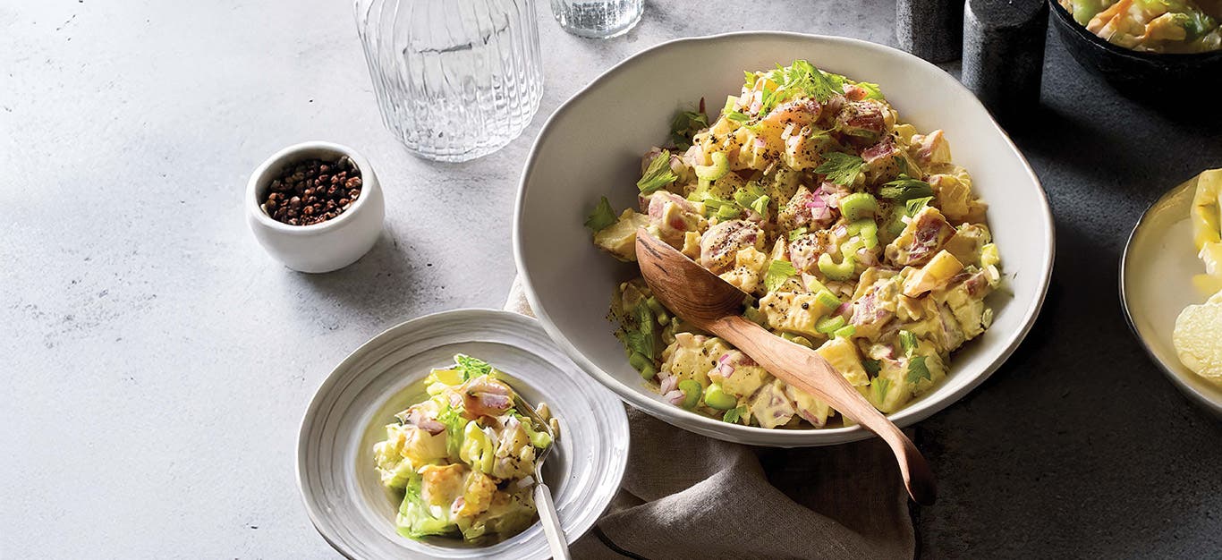 Del Sroufe's vegan Potato Salad in a bowl with a wooden serving spoon