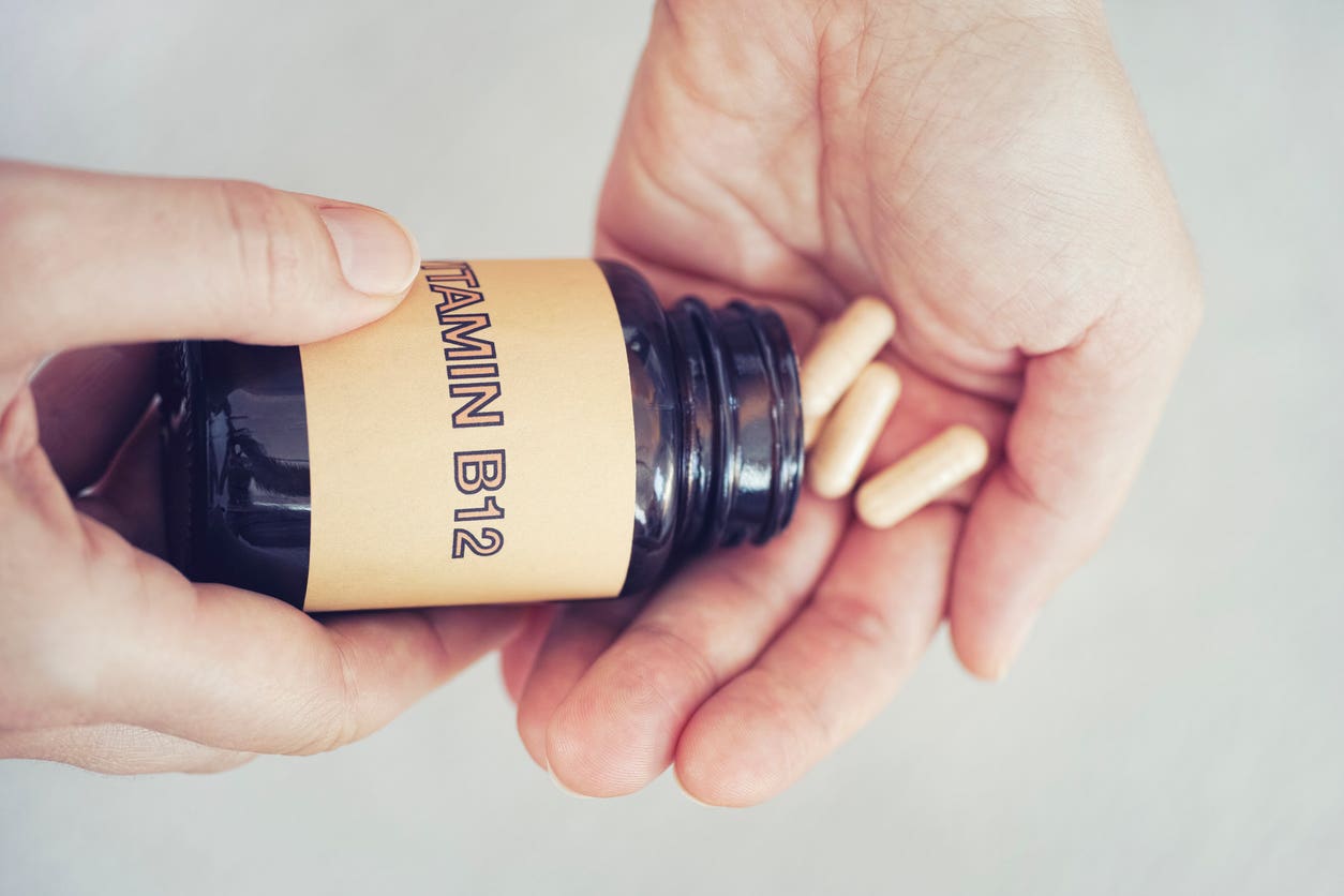 vitamin-b12 Hands pouring out a few vitamin b12 supplements from a plastic container