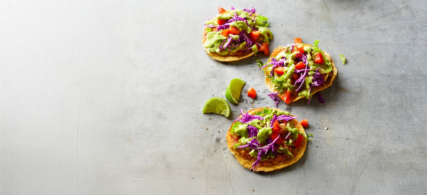 Three Southwest Chipotle Tostadas on a grey counter top with wedges of lime