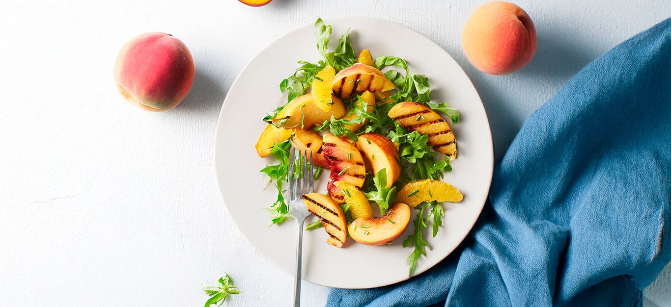 Peachy-Orange Arugula Salad on a white plate