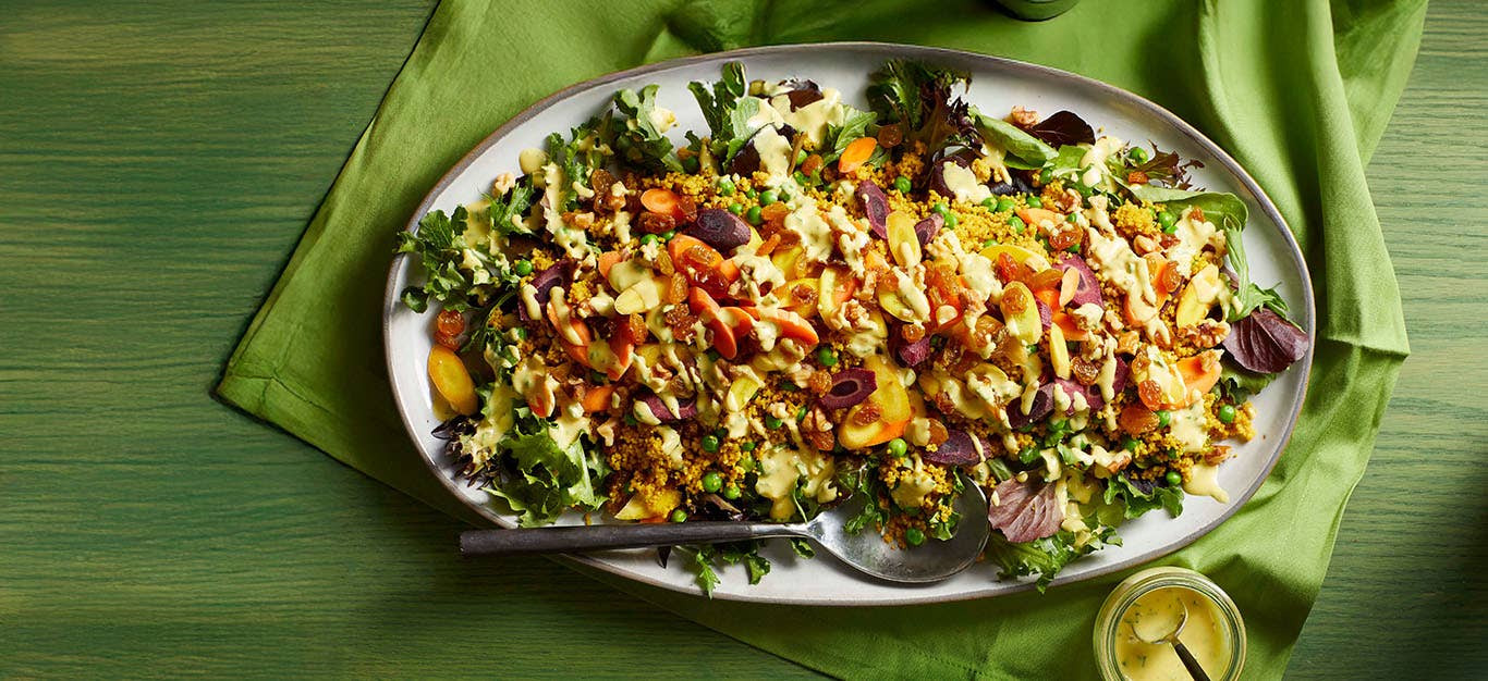 A large platter of Farmers Market Couscous Salad on a green table cloth