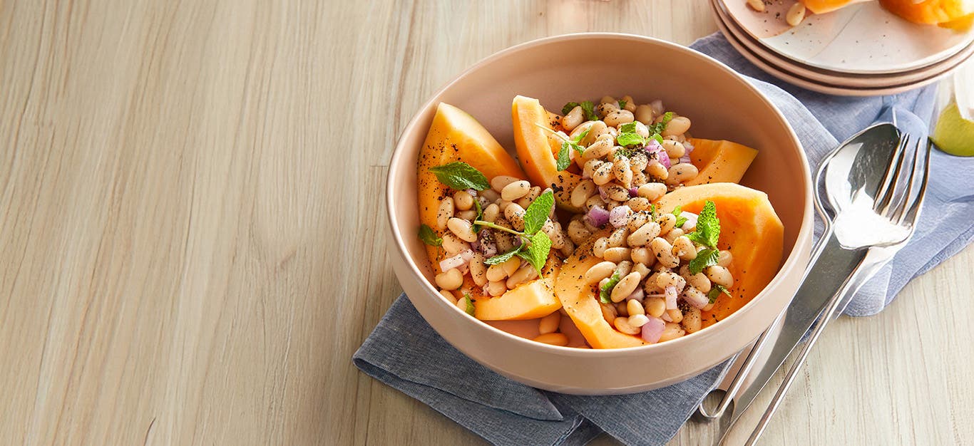 Melon and White Bean Salad in a bowl on a wooden counter