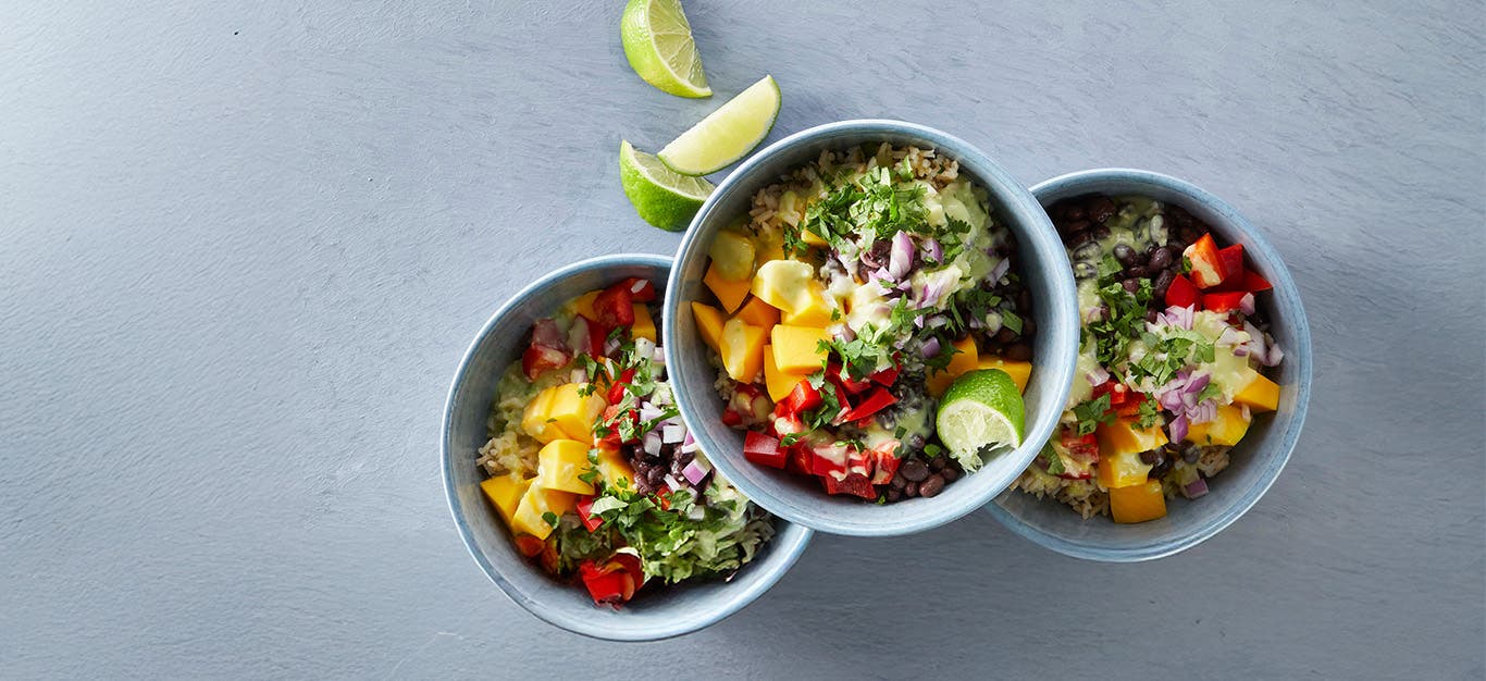 Two bowls of colorful Mango Rice Salad with a third on top, set against a grey background