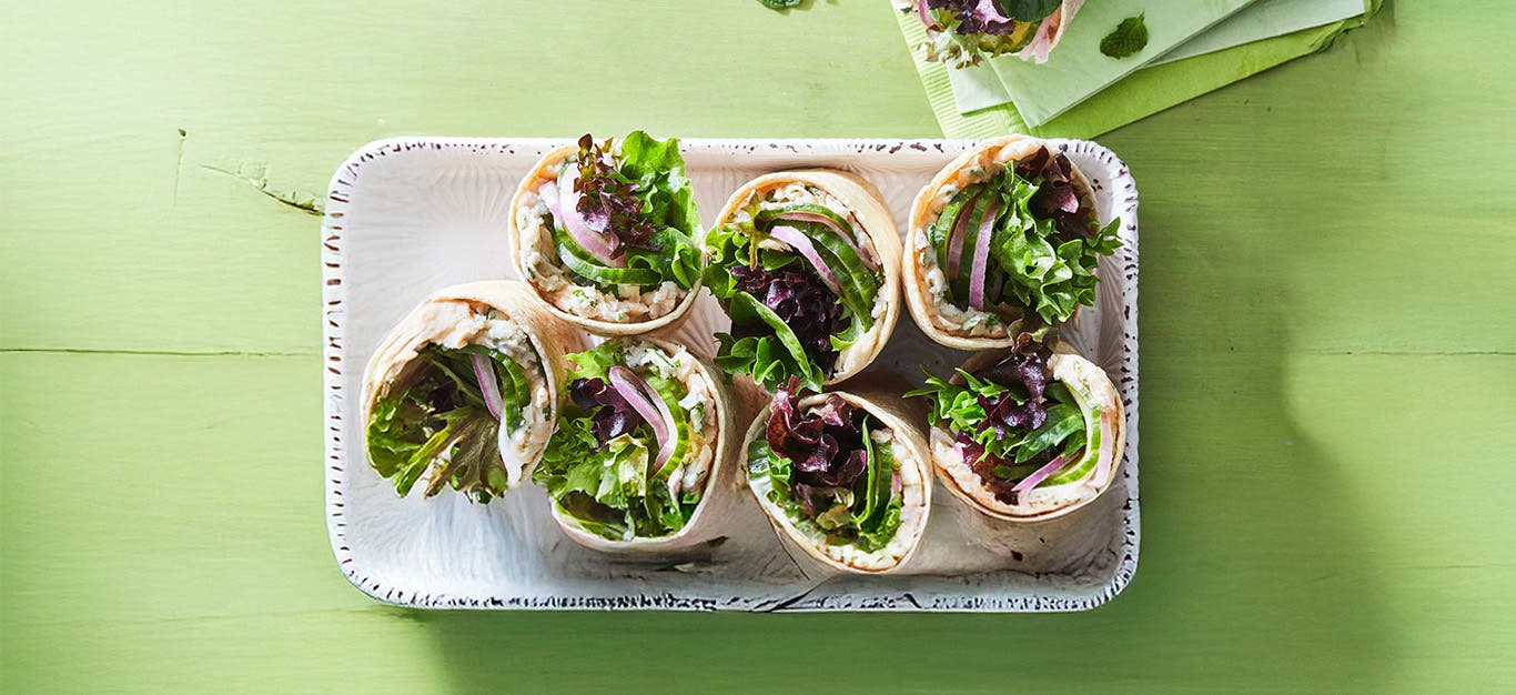 White Bean Wraps with Pickled Cucumber and Mint cut in half, arranged on a white platter, with cut side up
