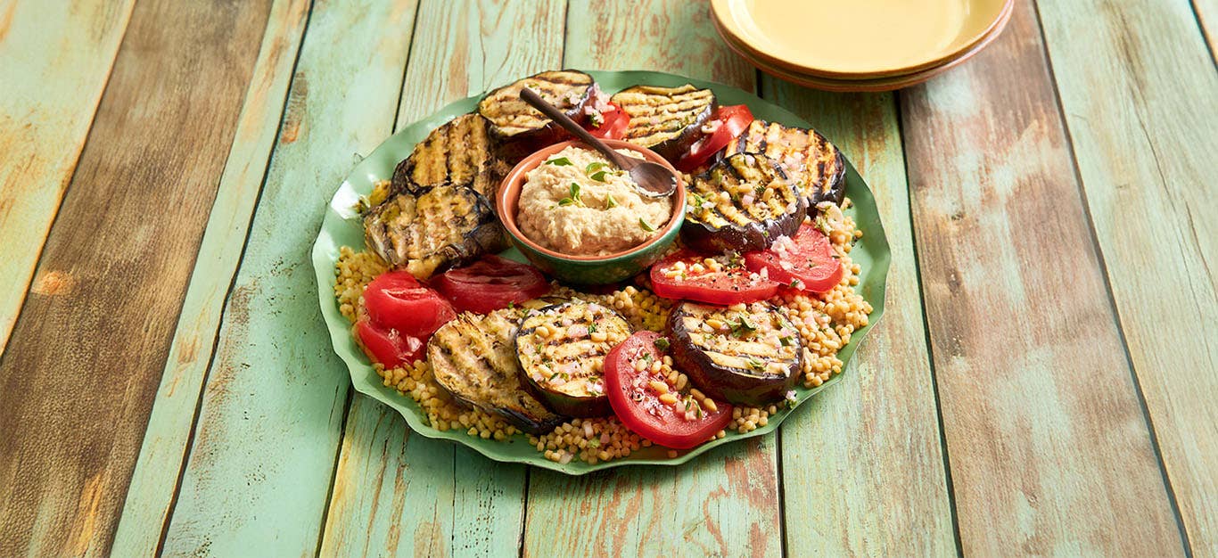 Greek-Style Grilled Eggplant Steak Supper on a platter with a bowl of hummus