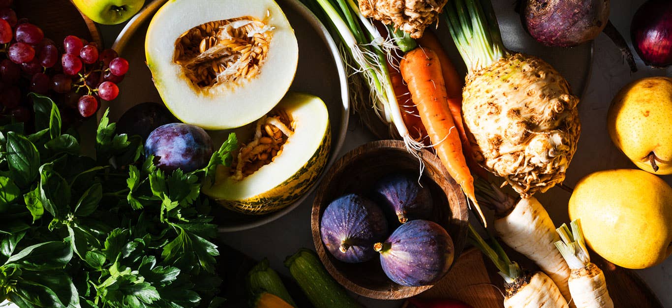 an abundant array of fall vegetables and fruits that are in season during autumn, including squash, carrots, parsnips, celeriac, figs, and leafy greens