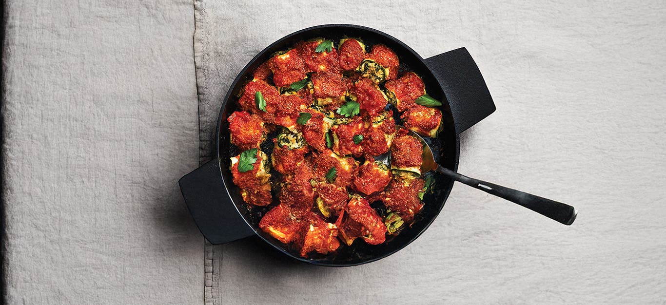 Zucchini Rollatini in a cast-iron skillet on grey cotton tablecloth