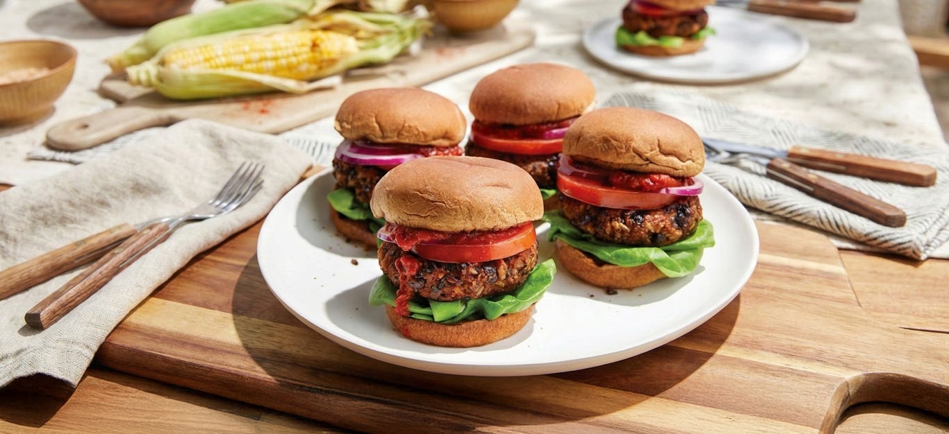 Four Grilled Black Bean Burgers on a large white plate on a chopping board