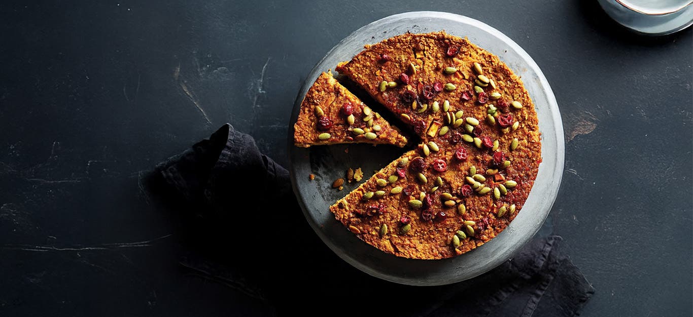 Vegan Holiday Torte on a plate with one sliced cut and ready to be served, on a dark grey background