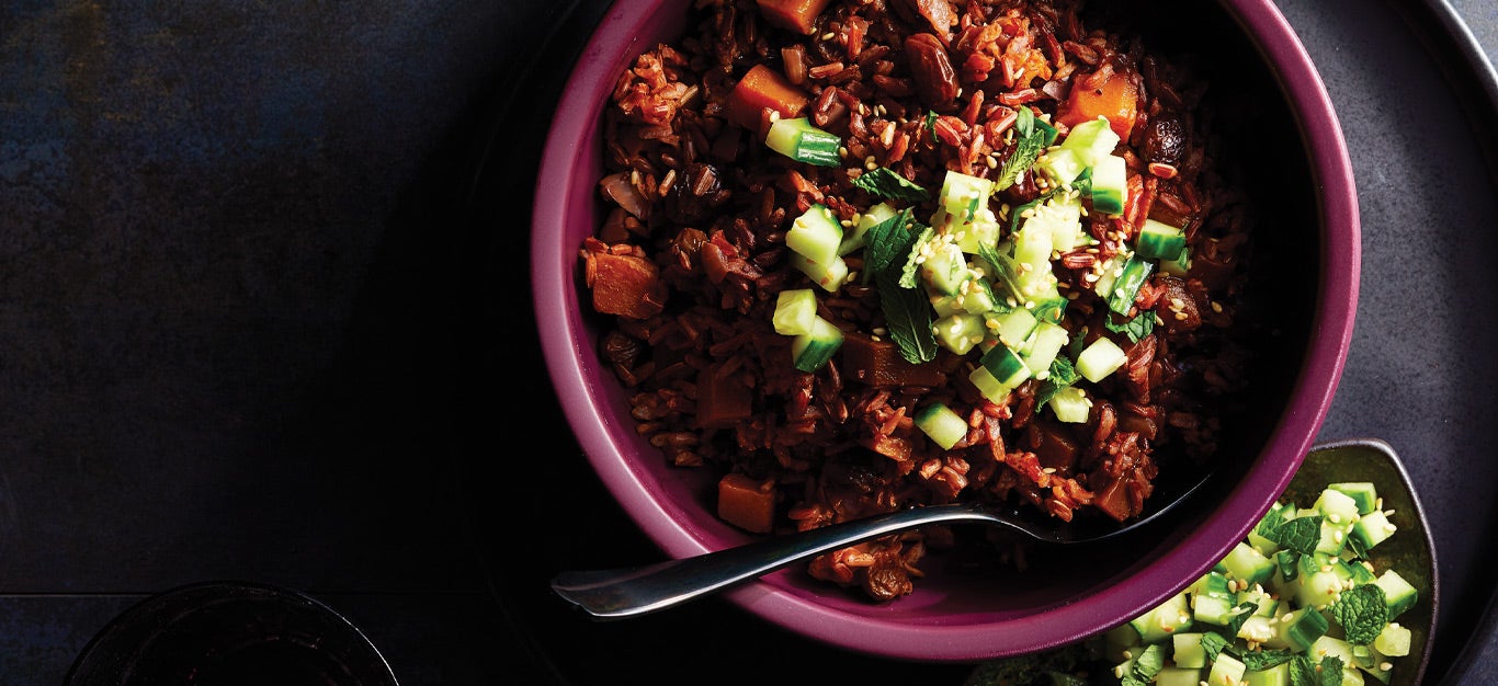 Middle Eastern Red Rice Pilaf in a purple ceramic bowl against a dark background