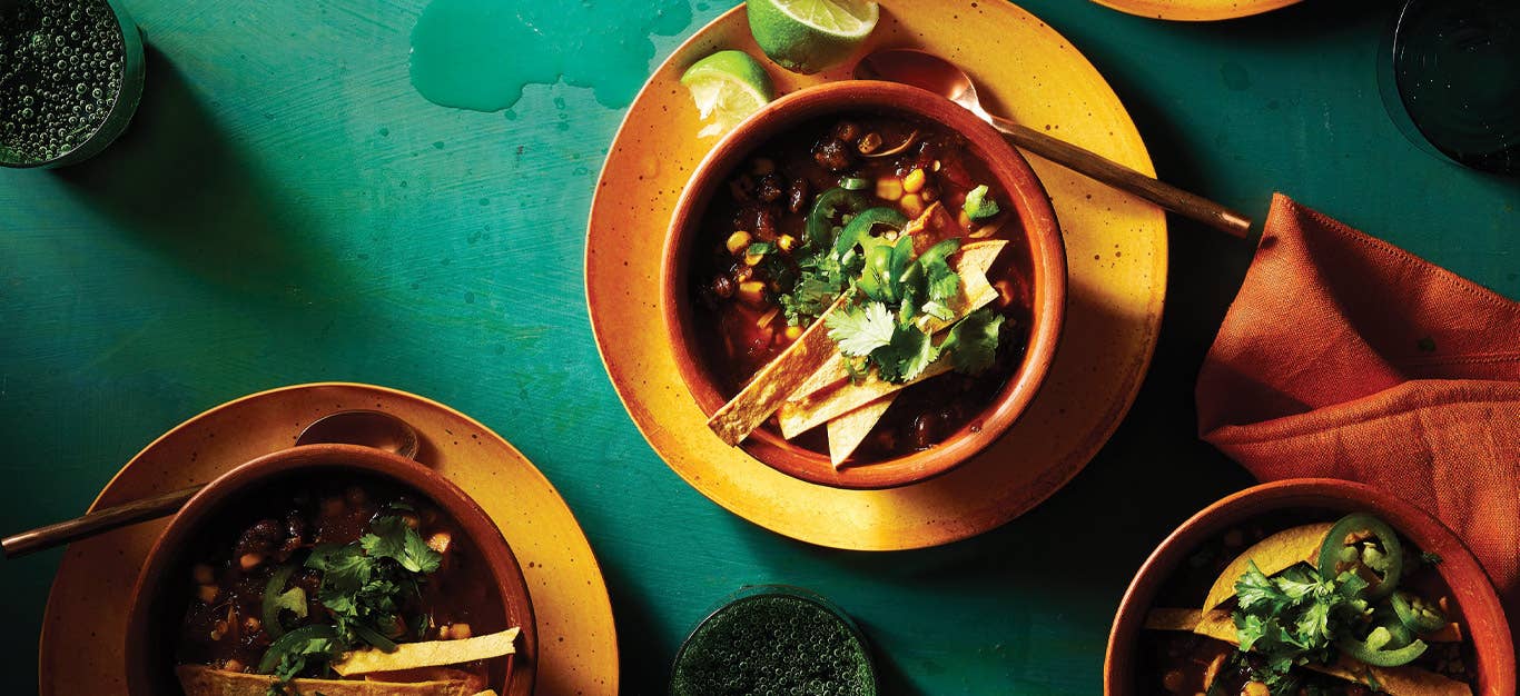 Vegan Taco Soup in terra cotta ceramic bowls against a green background