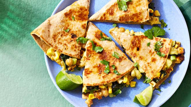 a vegan quesadilla with chickpeas and zucchini, shown sliced into four triangles on a plate