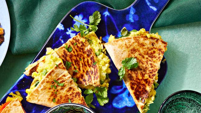 vegan quesadilla with creamed corn and poblano chiles, shown sliced, on a blue serving platter