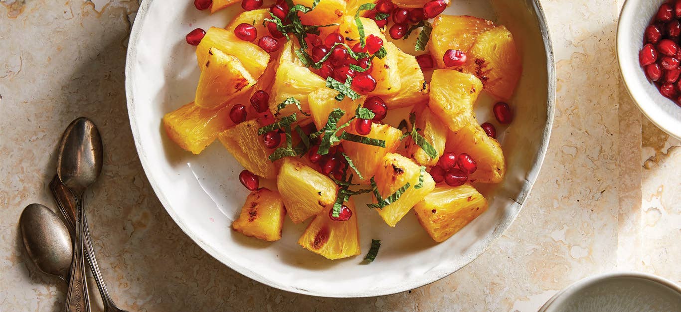 Roasted Pineapple with Fresh Mint and pomegranate arils in a white ceramic dish