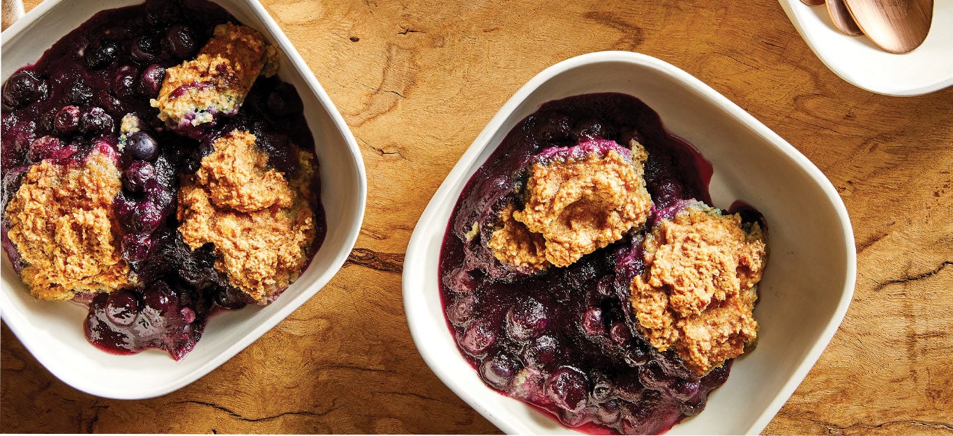Vegan Blueberry Cobbler in square white bowls against a wooden tabletop