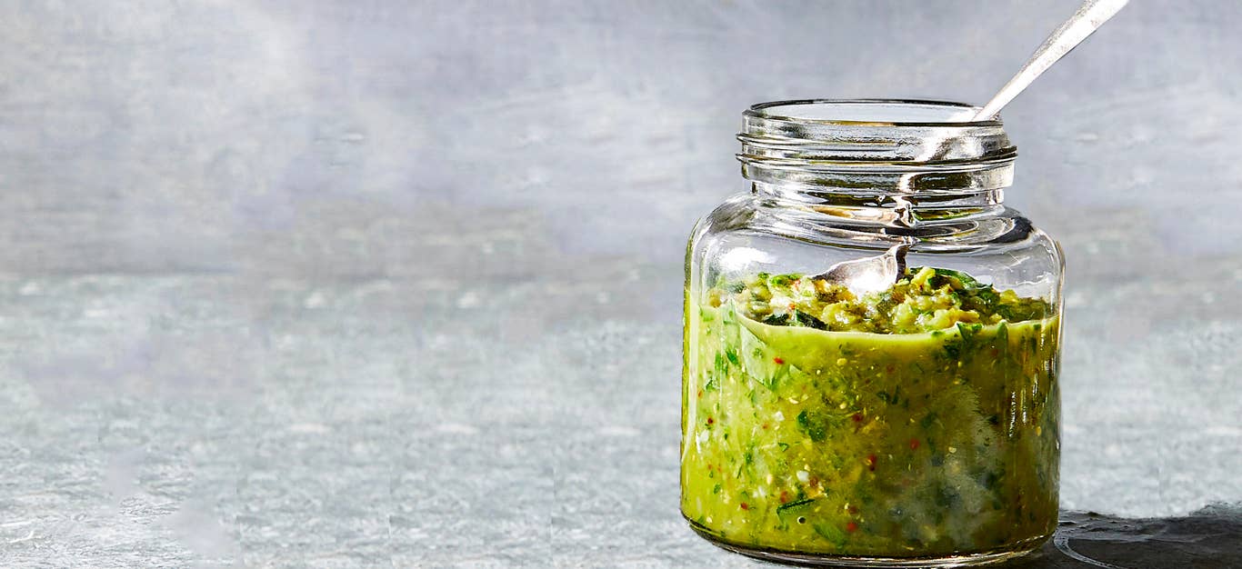 Spanish-Style Olive-Herb Sauce in a glass jar against a gray background