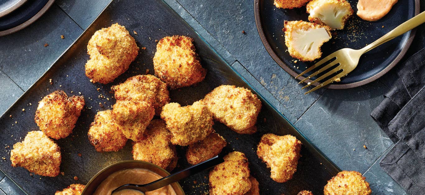 Air-Fried Cauliflower Poppers on a baking trap with a small bowl of Smoky Garlic Dipping Sauce