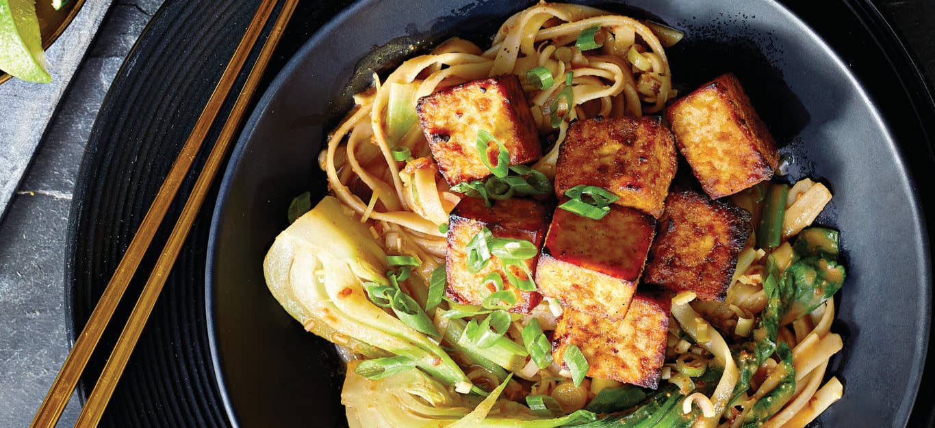 Thai Noodle Bowls with Crispy Air-Fried Tofu in a black ceramic bowl with bamboo chopsticks on the left hand side