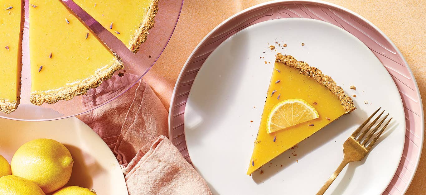 Lavender and Lemon Tart on a white and pink ceramic plate with a bowl of lemons in the lefthand corner