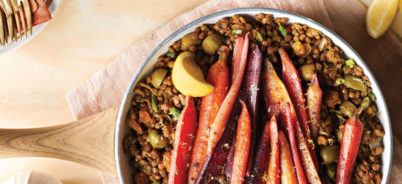Za'atar Carrots and Lentils in a ceramic dish with a wedge of lemon on a pale apricot cloth napkin