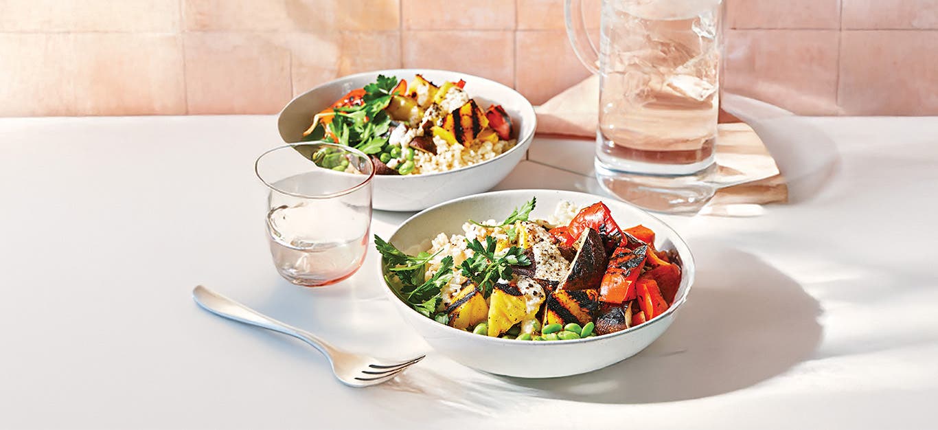 Grilled Pineapple Veggie Bowl in two bowls on a white table setting with a peach background