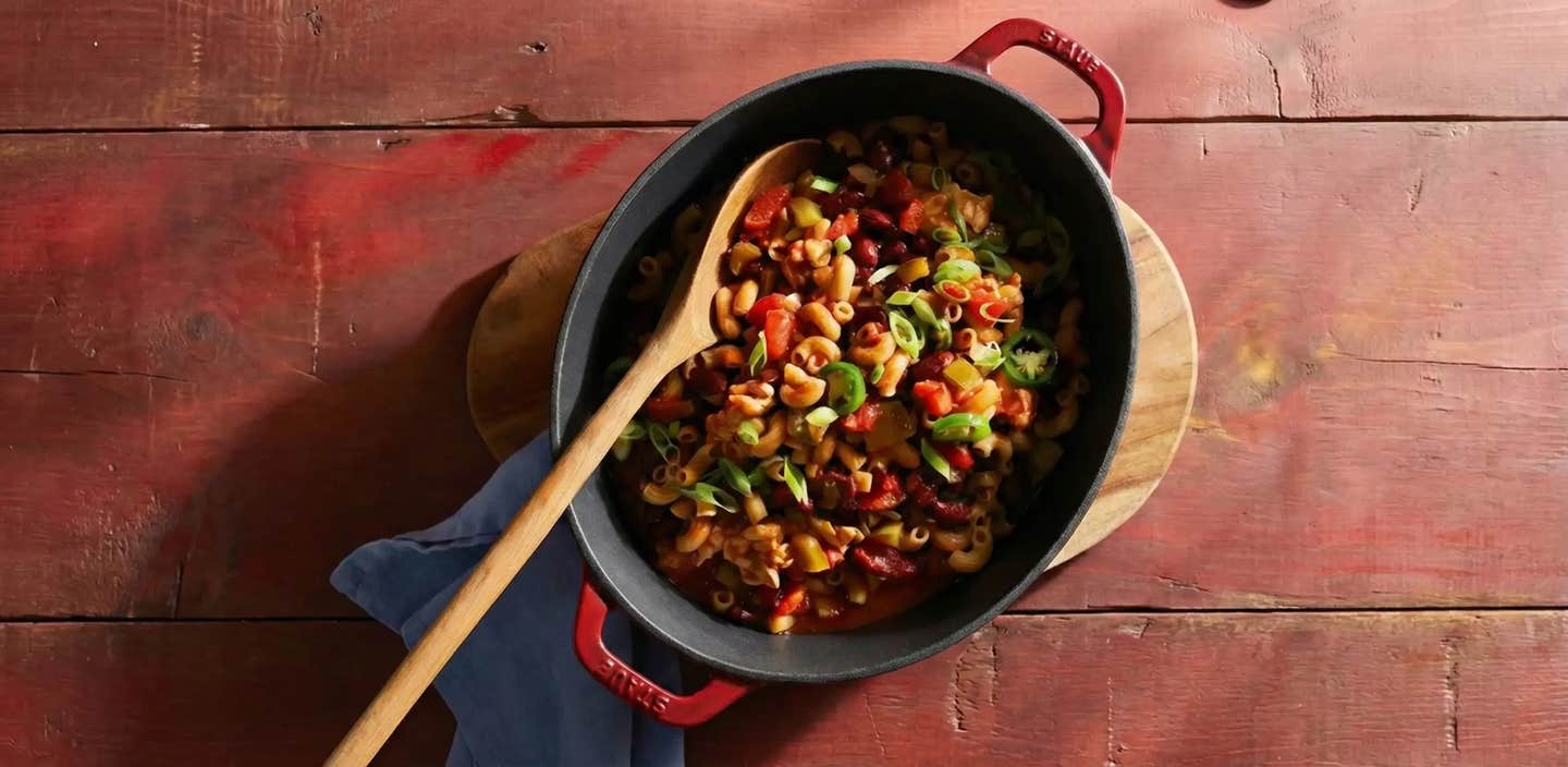 A dutch oven of One-Pot Spicy Tempeh Chili Mac with a wooden spoon