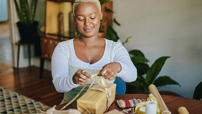 Young woman wrapping presents in living room
