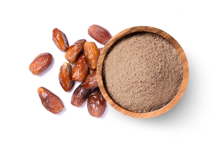 Pulverized dates (date sugar) in a bowl beside whole dates