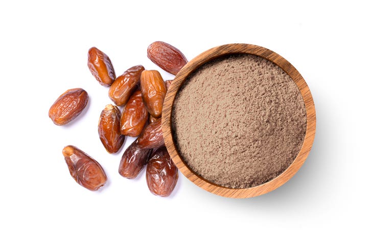 Pulverized dates (date sugar) in a bowl beside whole dates