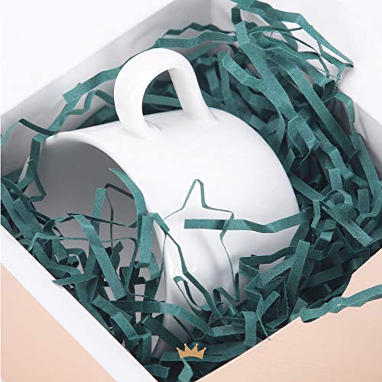 a white mug in a box of green crinkle paper