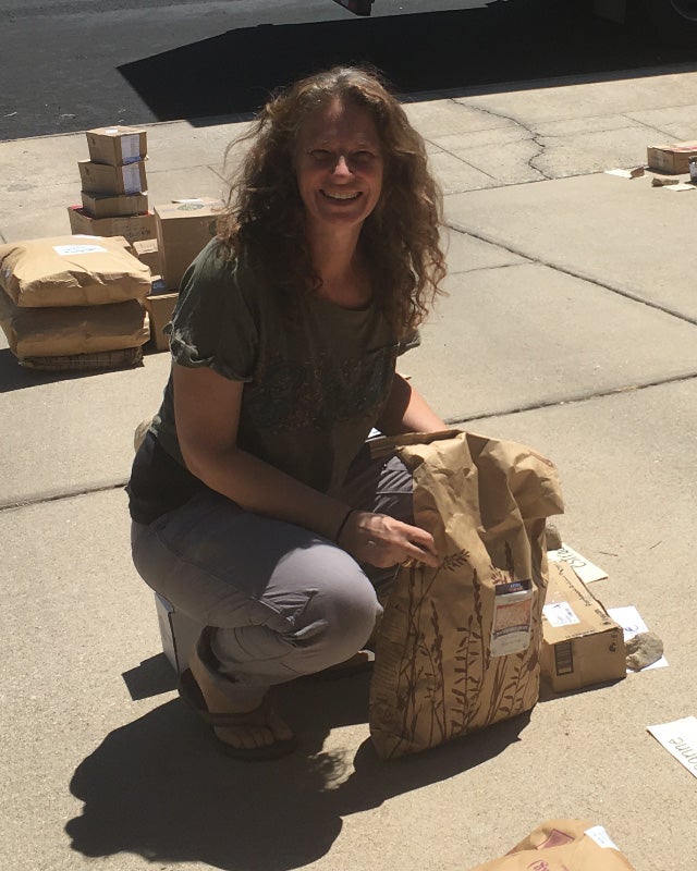 Author with a 25-lb bag of organic buckwheat on the sidewalk at the Azure Standard drop