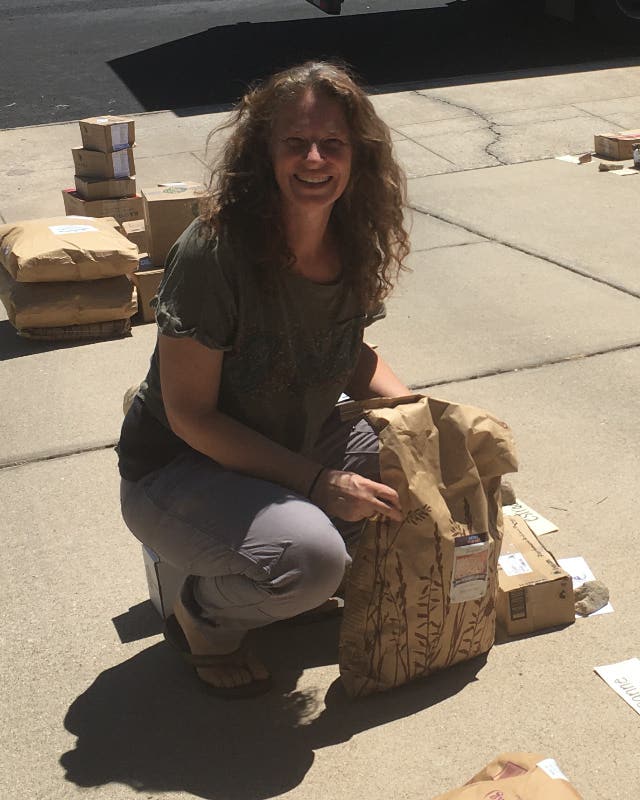 Author with a 25-lb bag of organic buckwheat on the sidewalk at the Azure Standard drop