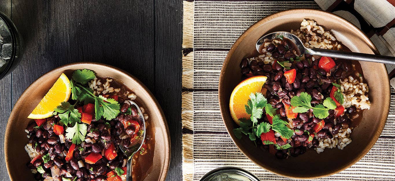 Two bowls of Vegan Feijoada (Brazilian Black Bean Stew) topped with fresh cilantro and a wedge of orange