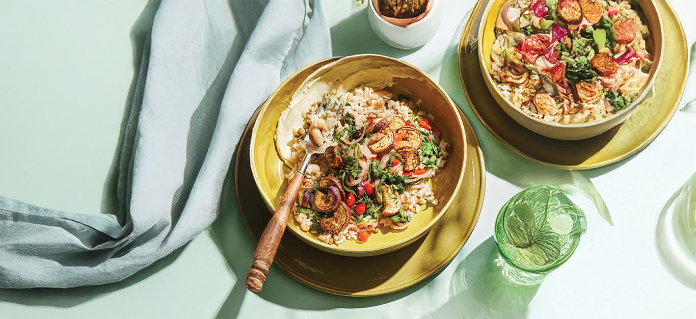 Two servings of Sautéed Eggplant with Hearty Grains on mustard ceramic bowls
