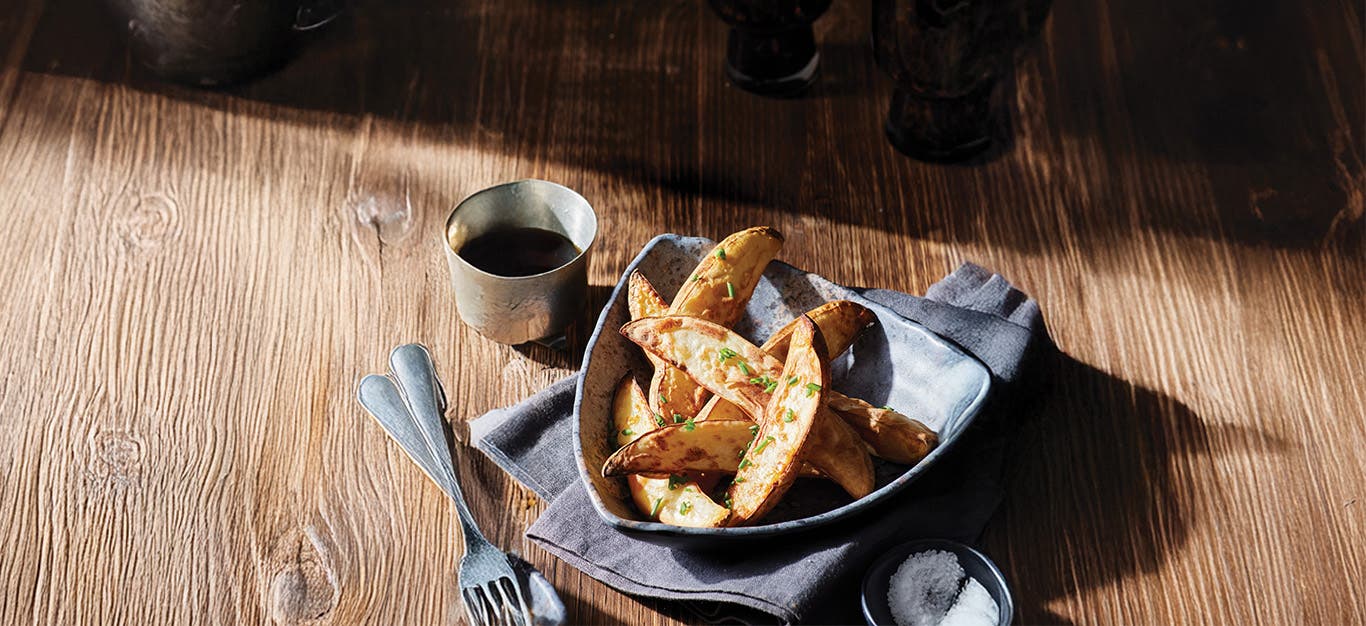 A bowl of Air-Fryer Pub Fries next to a small dipping bowl of malt vinegar