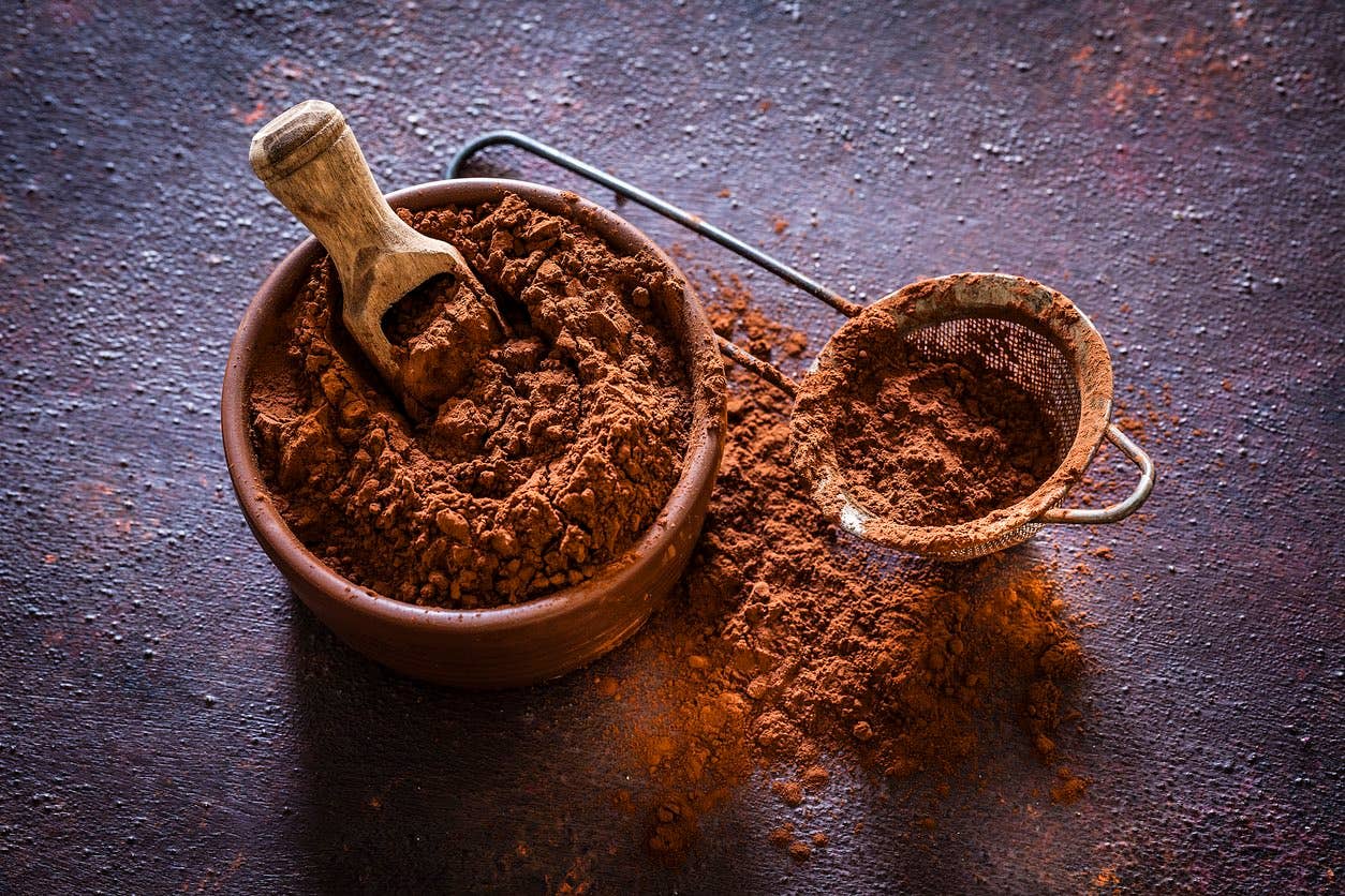 Cocoa powder in a brown bowl shot from above Brown bowl filled with cocoa powder shot on rustic table. Beside the bowl is a sieve also with cocoa powder.