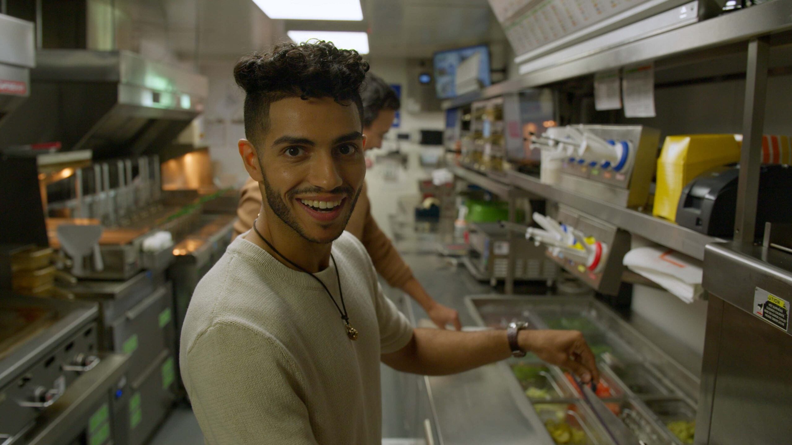 Actor Mena Massoud in the kitchen of a vegan restaurant