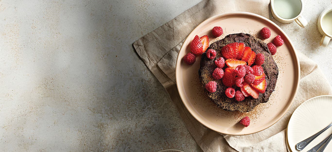 Slow-Cooker Chocolate Fudge Cake on a plate, topped with sliced strawberries and raspberries