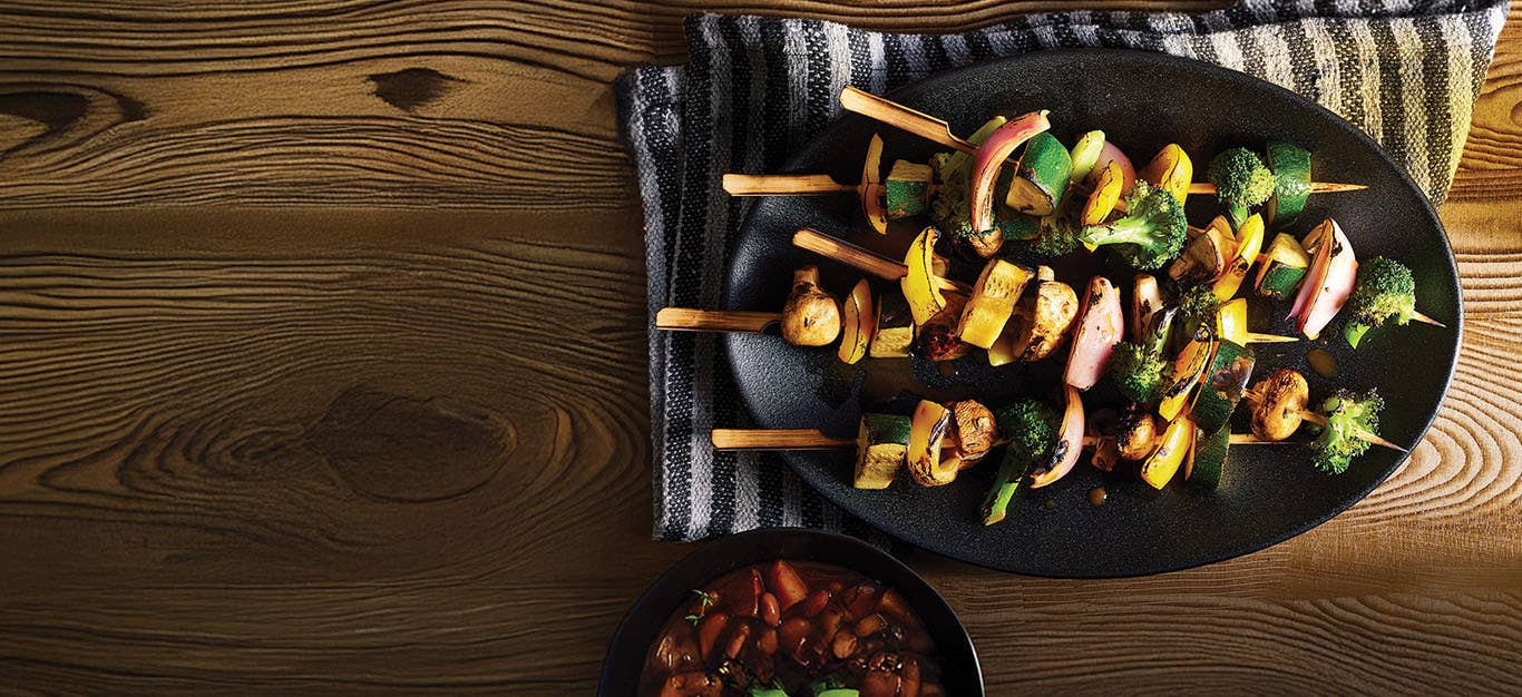 Vegetable Kabobs with BBQ Beans on a platter next to a small bowl of BBQ beans