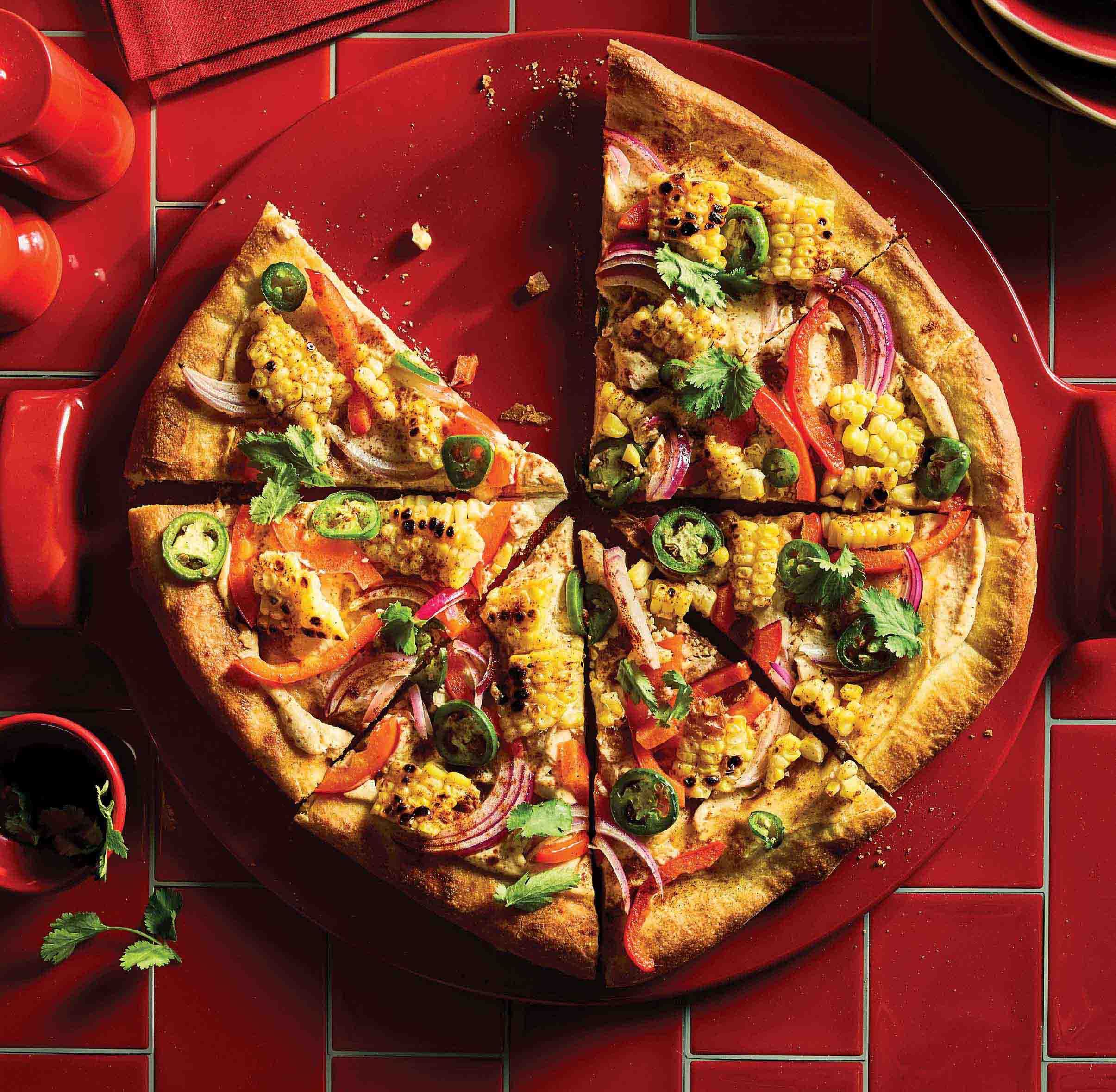 Red Emile Henry Pizza Stone topped with a wholesome homemade vegan pizza