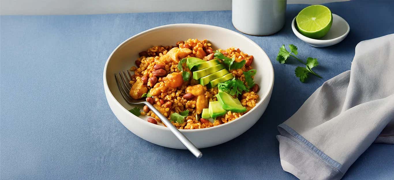 Red Beans and Rice Casserole with Plantains in a white bowl topped with sliced avocado