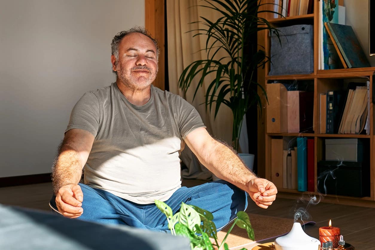 Man meditating in his living room, smiling slightly