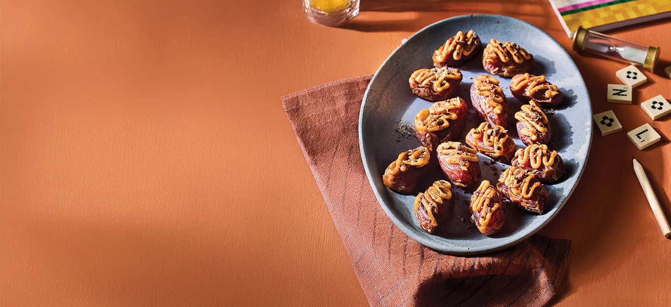 Kiki Nelson's Candy Bar Bites on a blue plate on a dark red kitchen towel with Scrabble tiles and a timer in the background