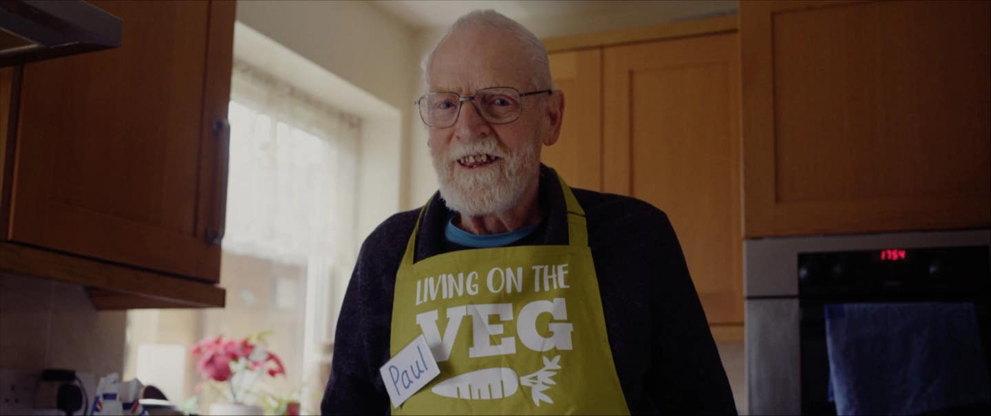Paul Youd in his kitchen wearing an apron that says LIVING ON THE VEG