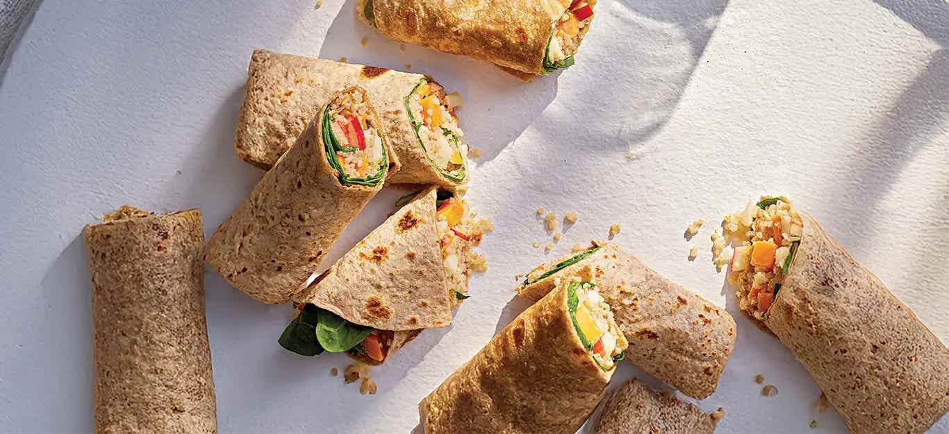 Quinoa, Apple, and Sweet Potato Wraps cut in half on a white counter