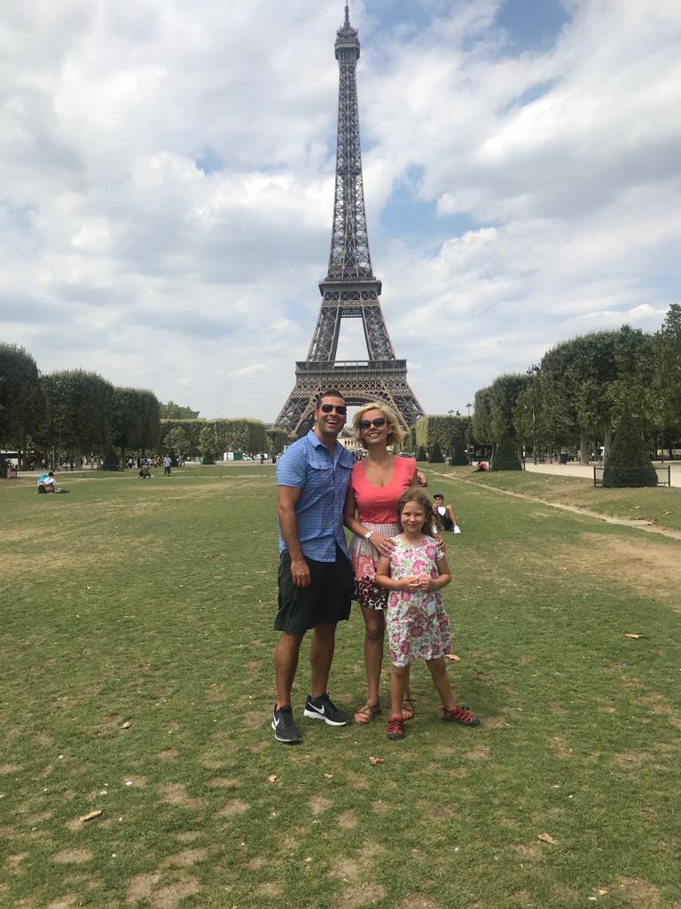 Weston McGee and his family, who follow a whole food plant based diet for health, standing in front of the Eiffel Tower on a sunny day