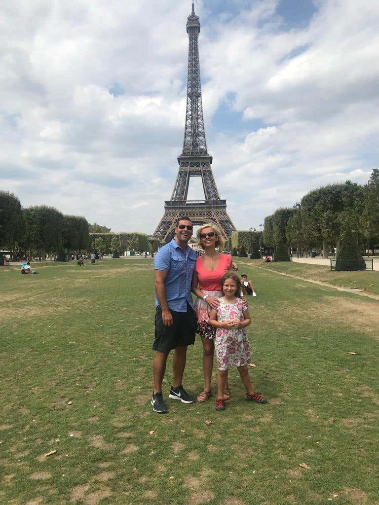 Weston McGee and his family, who follow a whole food plant based diet for health, standing in front of the Eiffel Tower on a sunny day