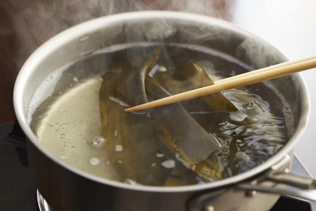 kombu broth Vegan kombu dashi broth in a pot of water, with chopsticks lifting the dashi out of the pot