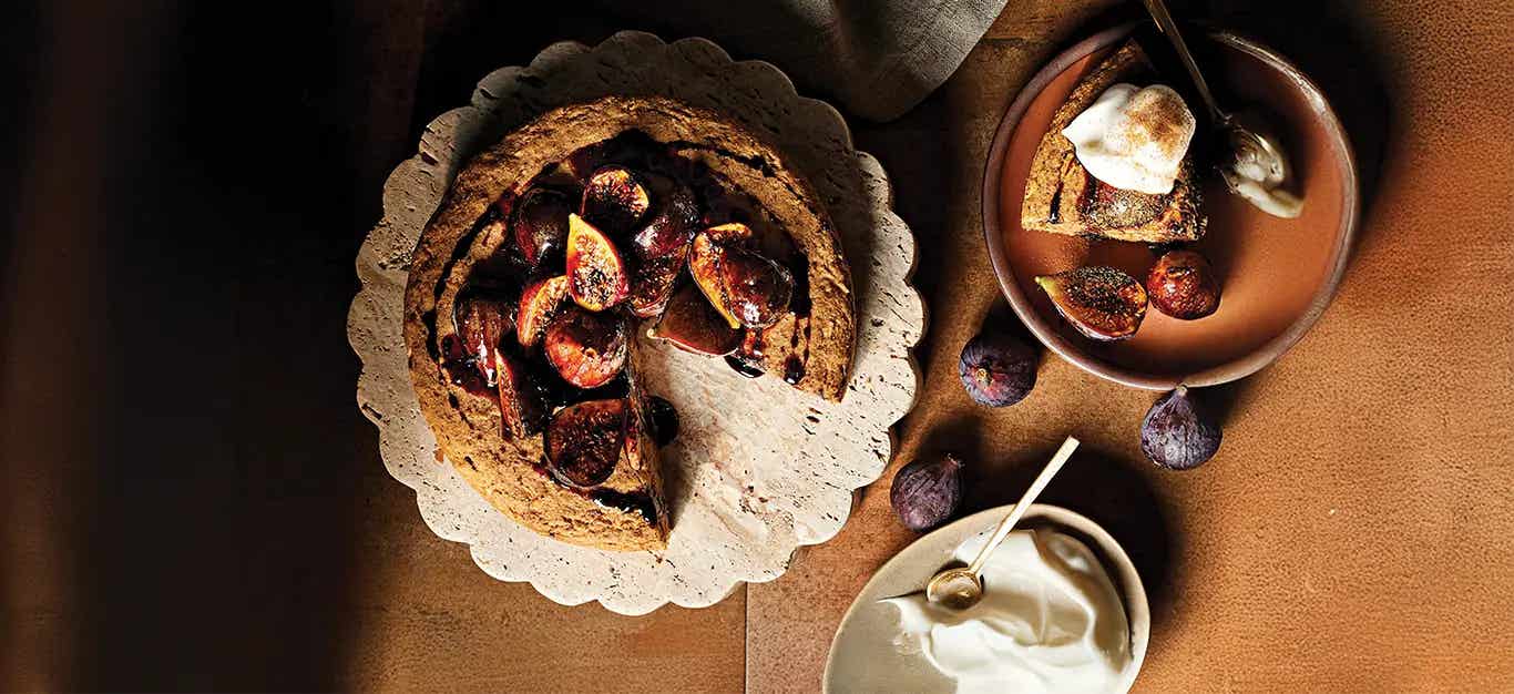 Vegan Apple Cake with Maple-Glazed Figs on a plate, with one slice removed and served on a plate with a dollop of aquafaba whipped cream